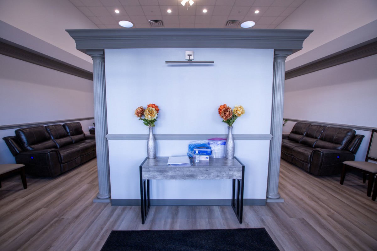 A modern reception area with a table, vases filled with colorful flowers, and comfortable seating.