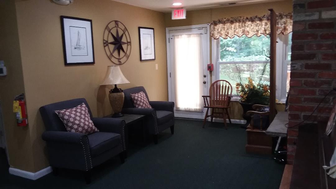 Cozy living room with armchairs, decorative wall art, and a sunlit window.