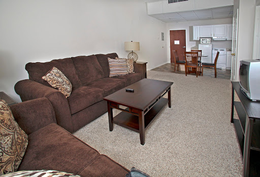 A cozy living room featuring a brown sofa, a wooden coffee table, and soft carpeting.