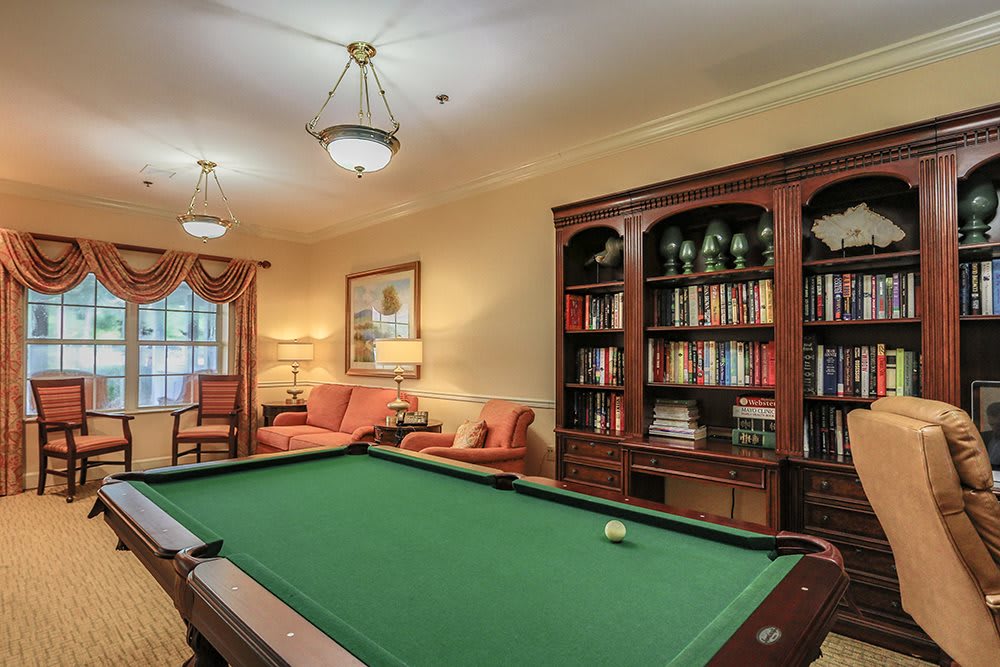 A cozy billiard room featuring a pool table, elegant bookshelves, and comfortable seating.
