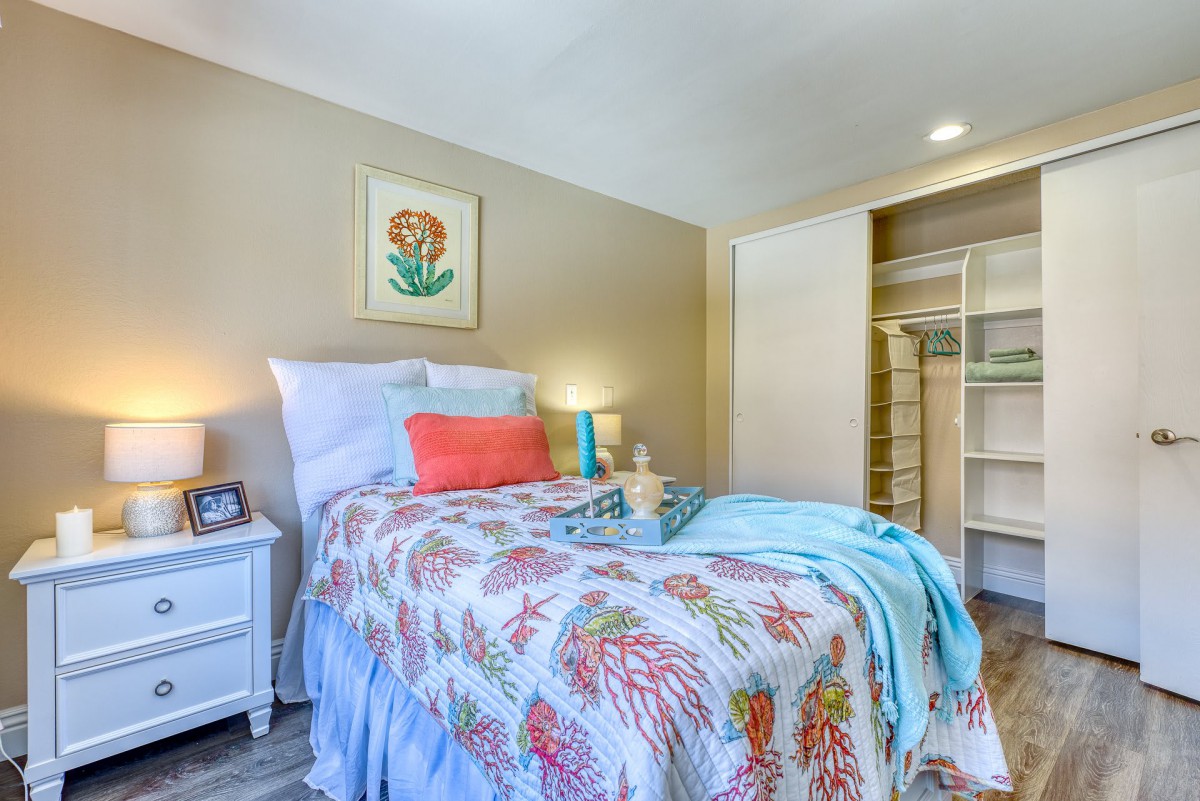 A cozy bedroom with colorful bedding and a neatly organized closet.