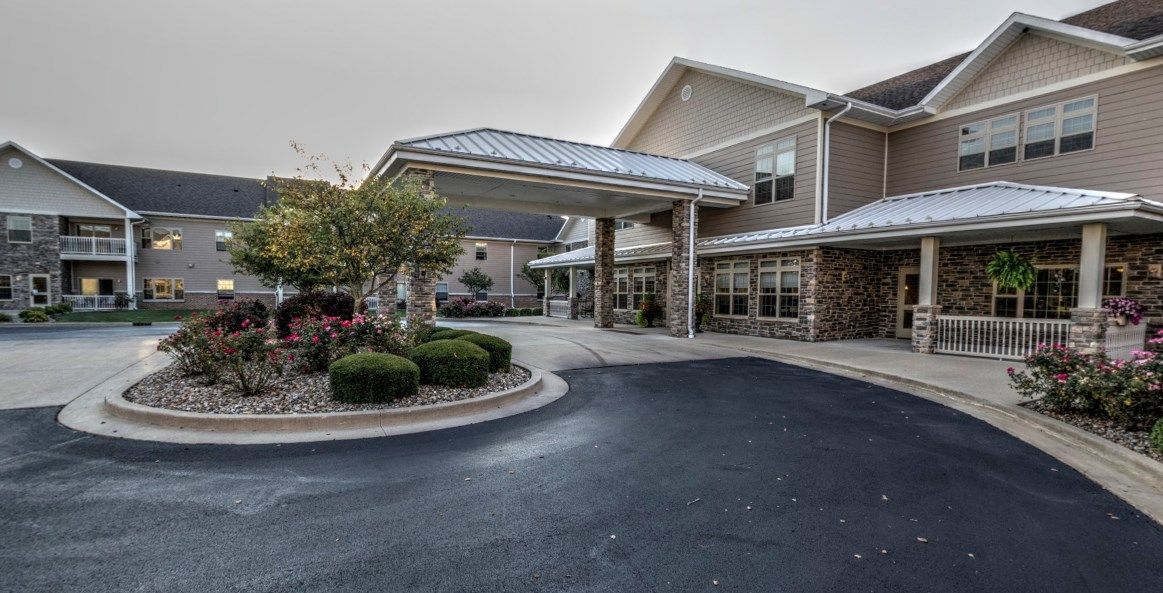 A well-maintained building entrance with a covered driveway and landscaped surroundings.