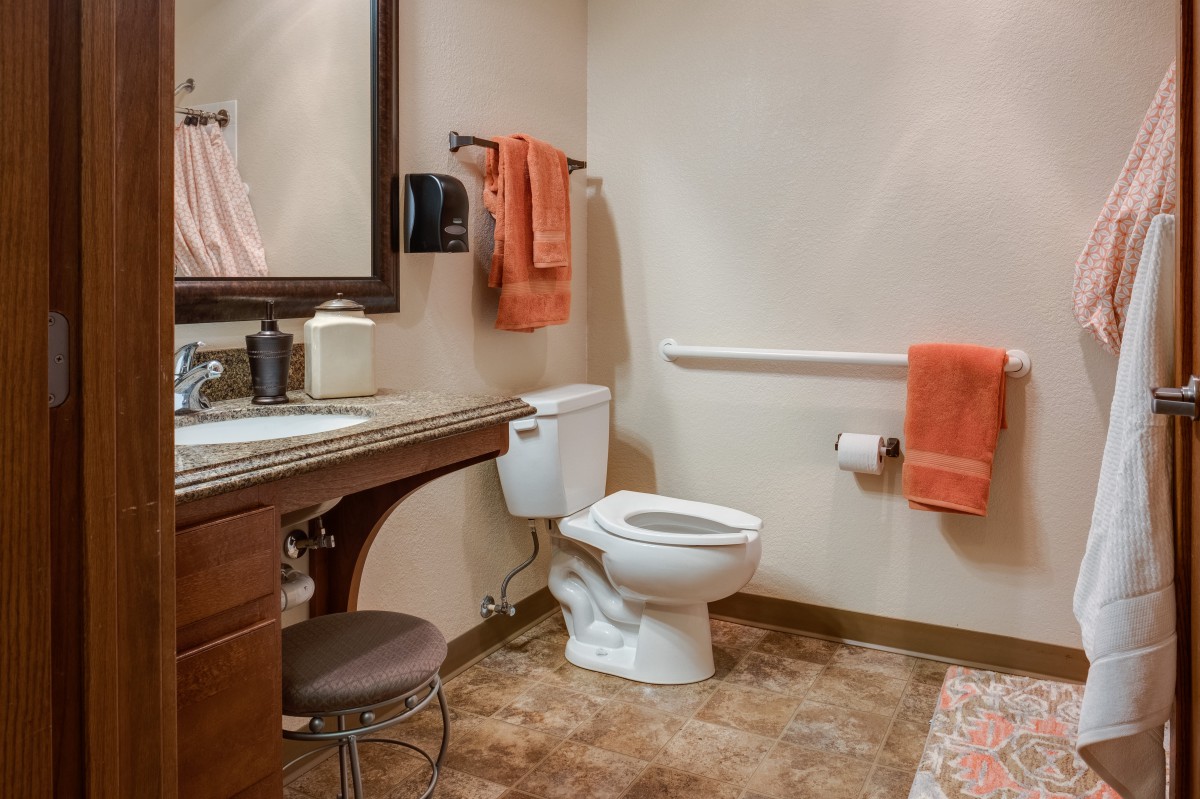 A well-organized bathroom with a toilet, sink, and mirror.
