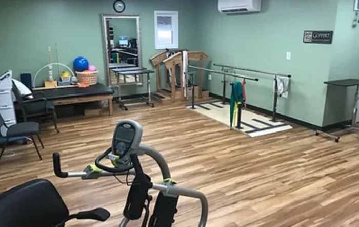 A rehabilitation therapy room equipped with various exercise machines and training tools.