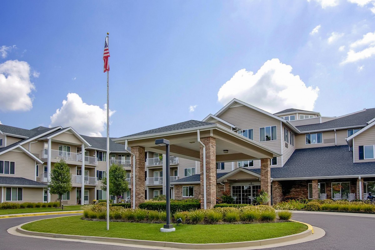 A modern residential apartment building with a well-maintained exterior and surrounding greenery under a blue sky.