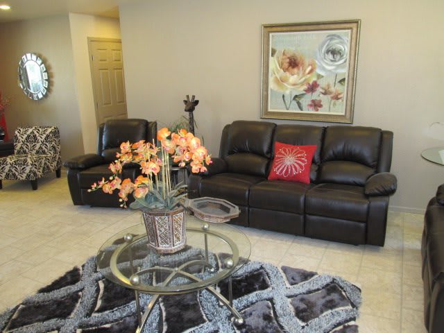 A cozy living room with leather seating and floral decor.