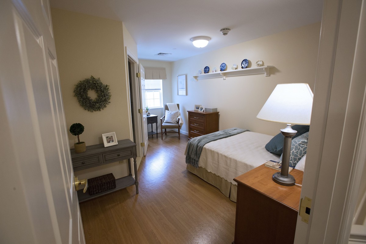 A cozy bedroom with simple decor and wooden flooring.