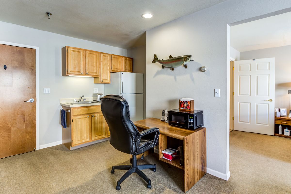A small office area with a desk and chair adjacent to a kitchenette.