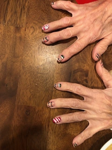 A pair of hands with creative nail art rested on a wooden table.