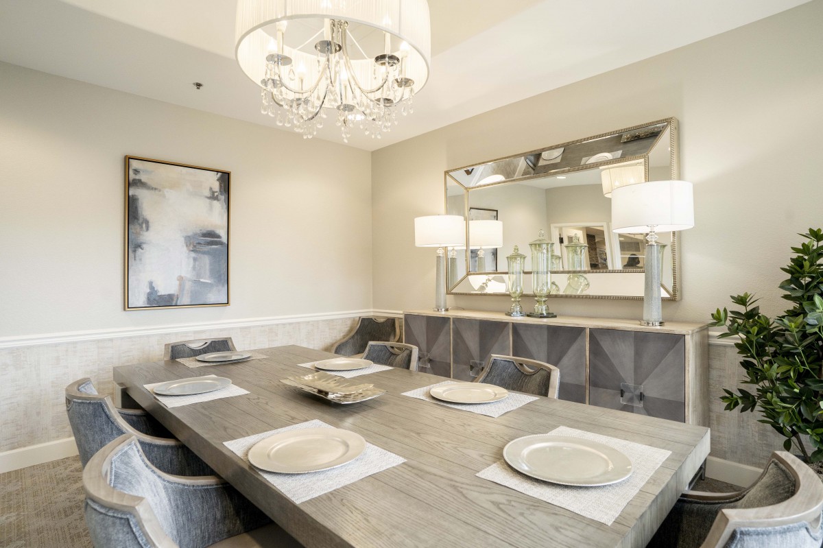 A modern dining room featuring a large wooden table, elegant chandelier, and stylish decor.