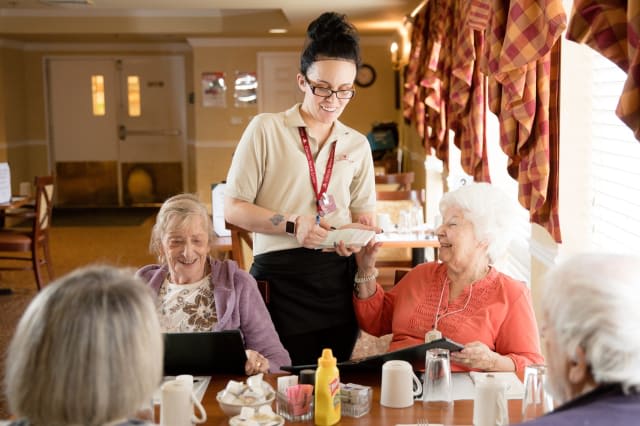 A caregiver assists elderly residents during a meal at a nursing home.