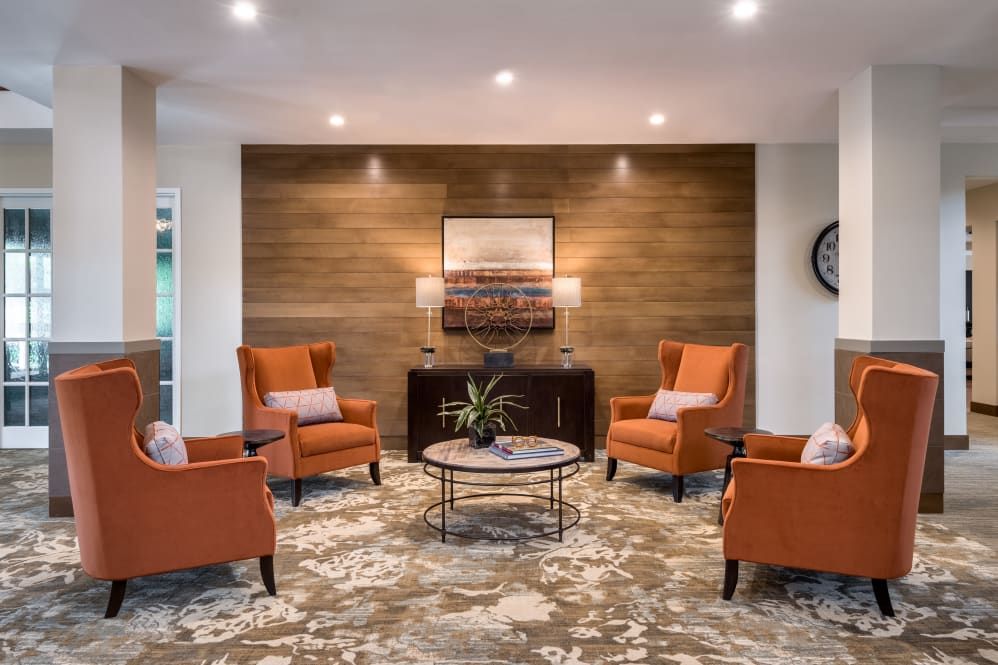 A cozy living room with orange chairs and a wooden accent wall.