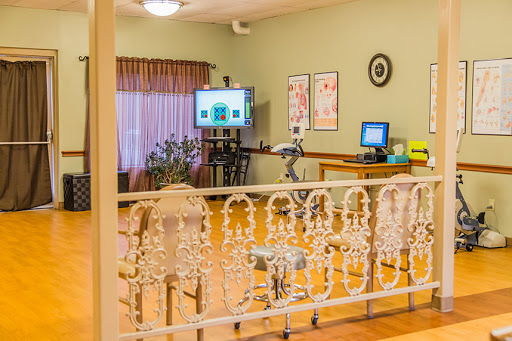 A spacious room equipped with a computer workstation and medical equipment, featuring warm lighting and inviting decor.