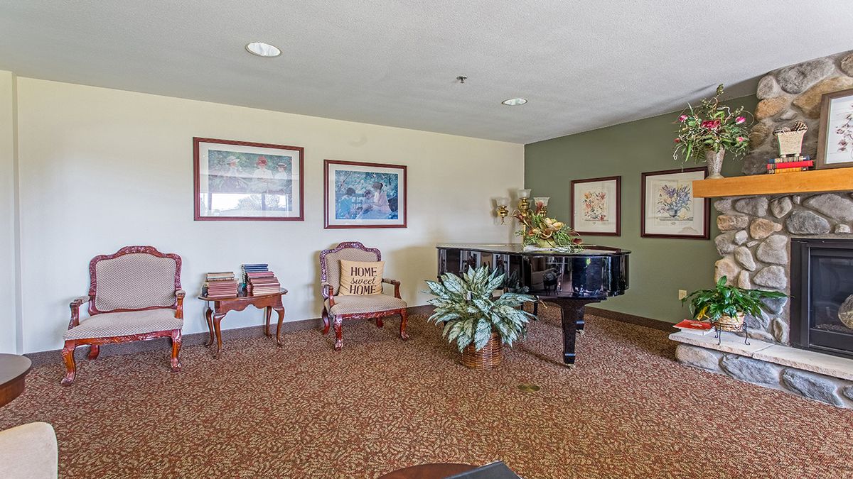 A cozy room featuring a grand piano, elegant furniture, and framed artwork on the walls.