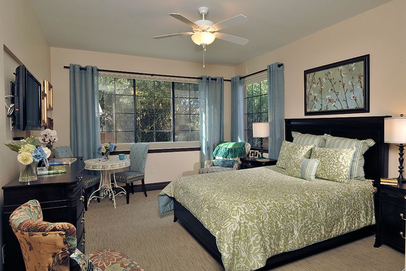 A well-decorated bedroom with a comfortable bed, large windows, and stylish furnishings.