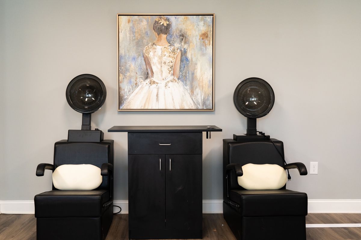 A modern salon setup with two hair drying chairs and a stylish artwork on the wall.