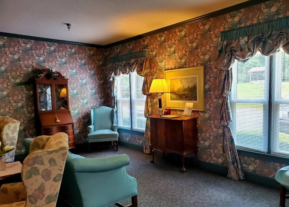 A cozy living room with vintage furniture and floral wallpaper.