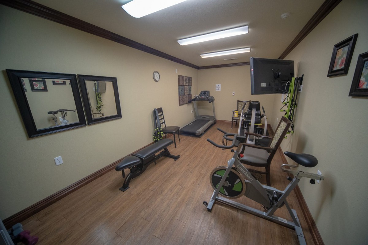A compact gym with various fitness equipment, including a treadmill and bench.