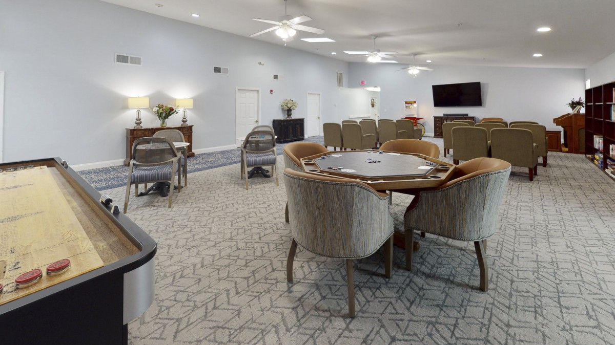 A modern living room with a dining table, chairs, and a mounted television.