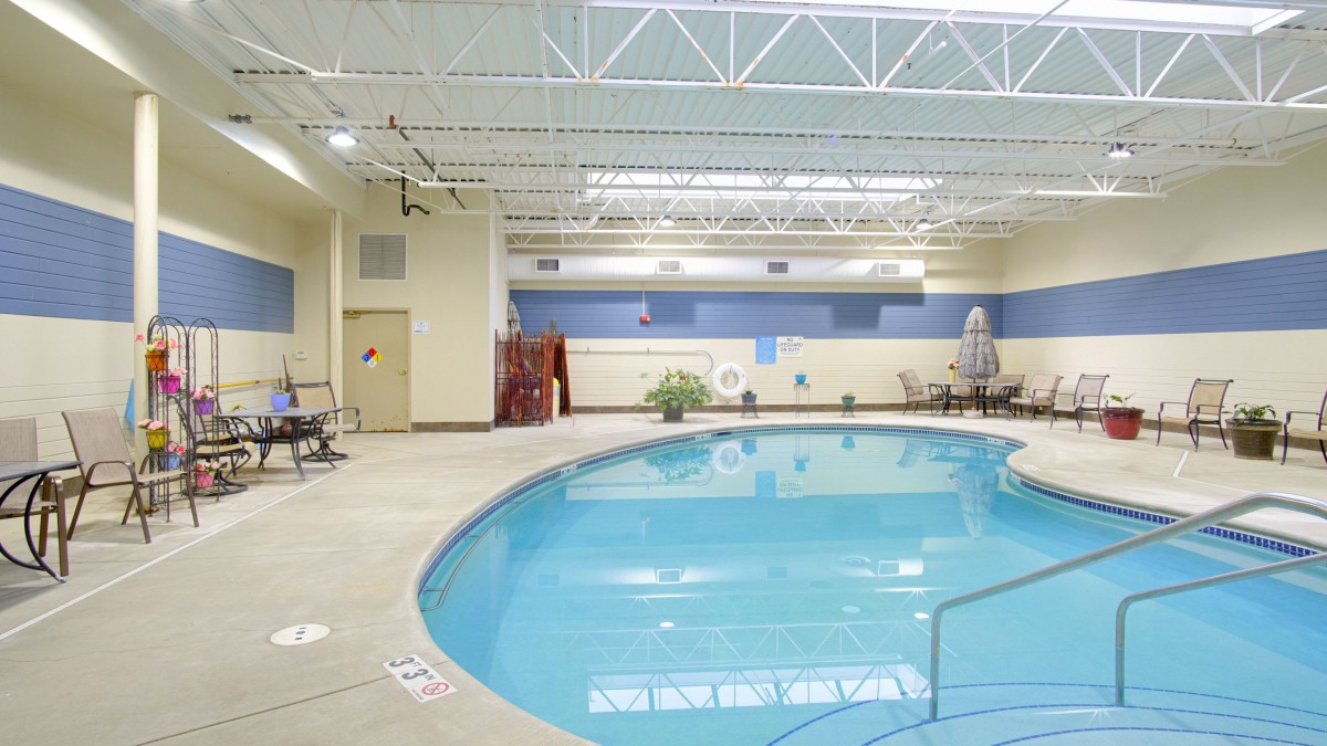An indoor swimming pool with seating area and tiled flooring.