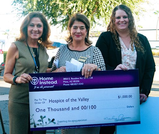 A donation of $1,000 is presented to 'House of the Valley' during a community event.