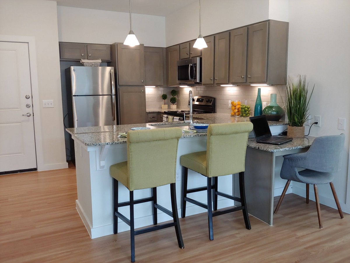 Modern kitchen with stainless steel appliances and a central island featuring bar stools.