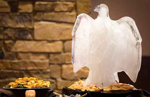 An elegant ice sculpture of an eagle stands proudly amidst a delicious food display.