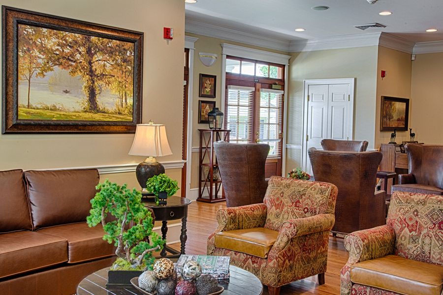 A cozy living room with comfortable seating, decorative plants, and artwork on the wall.