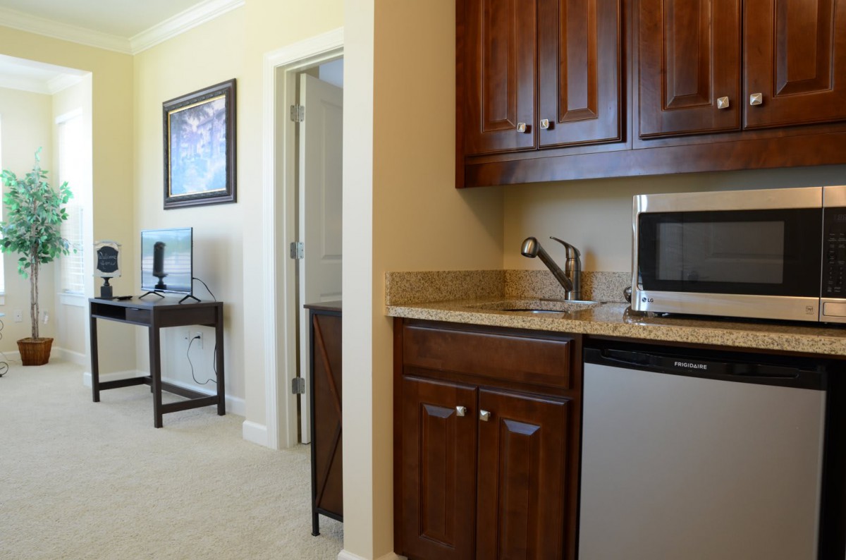 A compact kitchenette with wooden cabinets and modern appliances adjacent to a cozy living area.