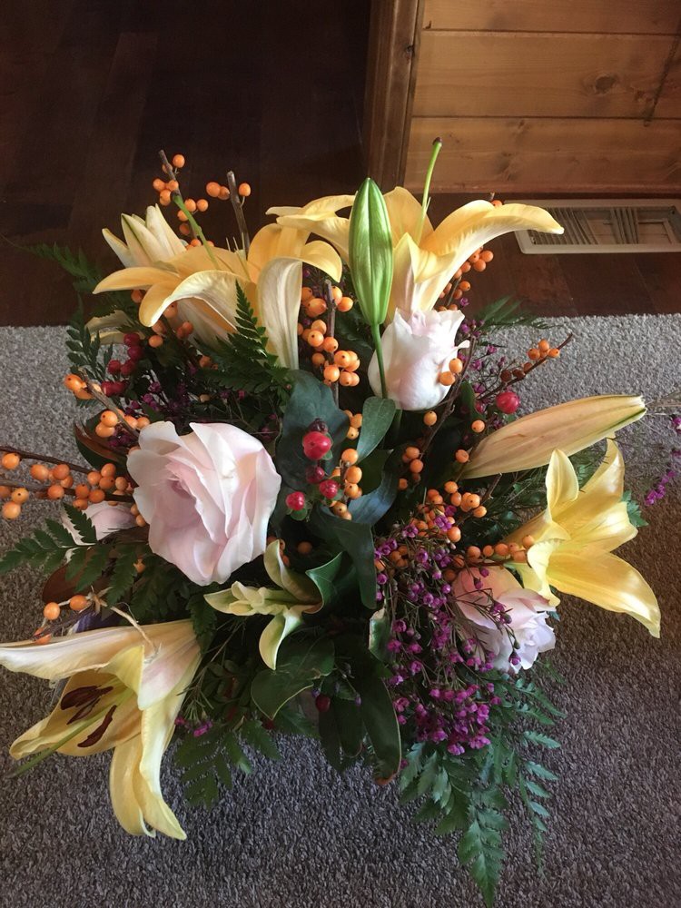 A vibrant bouquet featuring yellow lilies, pink roses, and decorative berries.