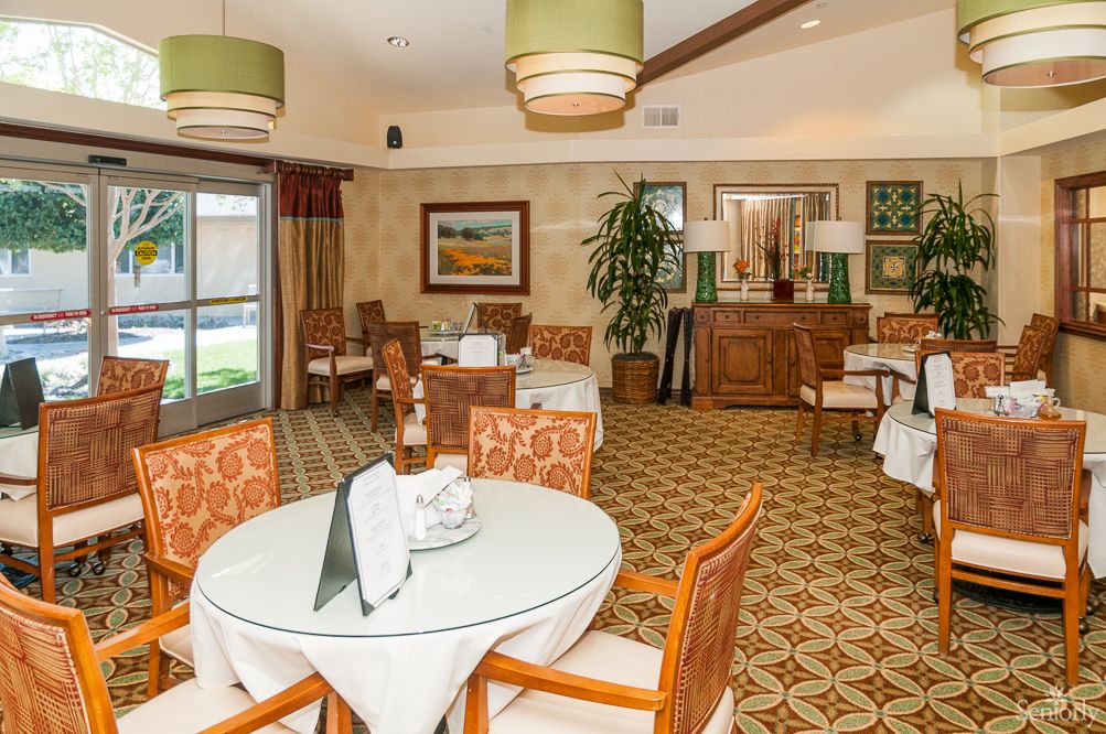 A well-appointed dining room featuring elegantly set tables, comfortable chairs, and warm lighting.