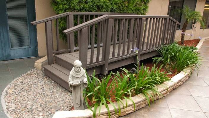 A small garden bridge with a statue surrounded by greenery.