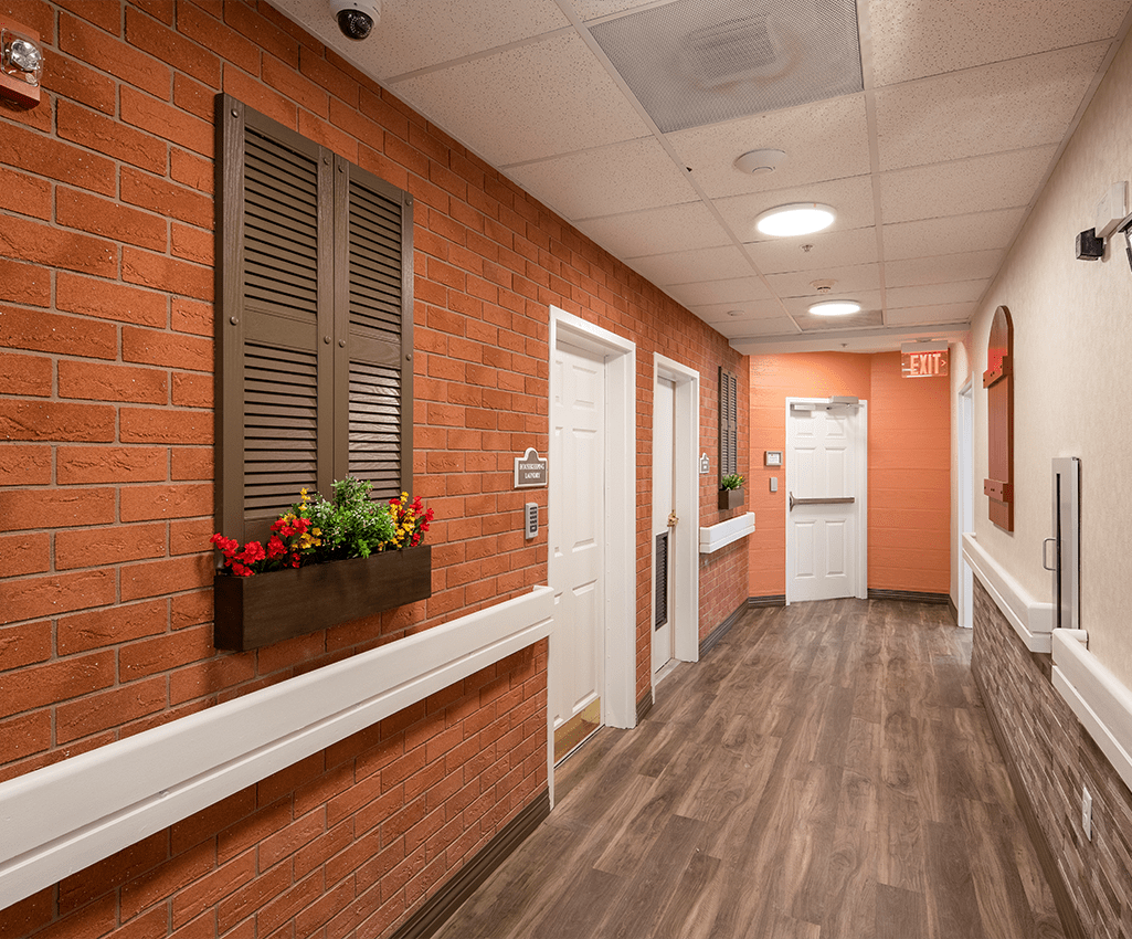 A hallway with brick walls, wooden flooring, and decorative window shutters.