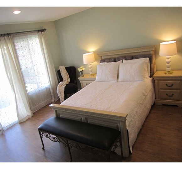 A cozy bedroom with a wooden bed, nightstands, and natural lighting.