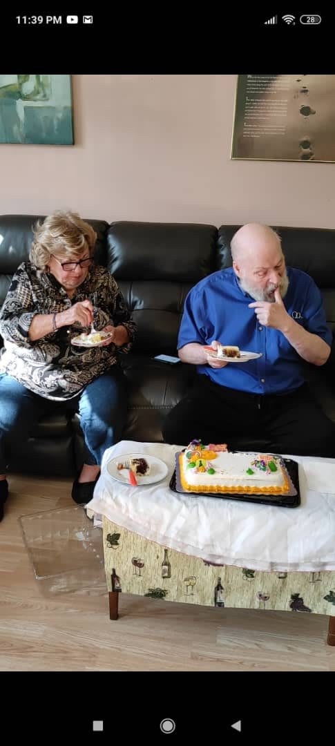 Two people enjoying cake on a sofa during a celebration.