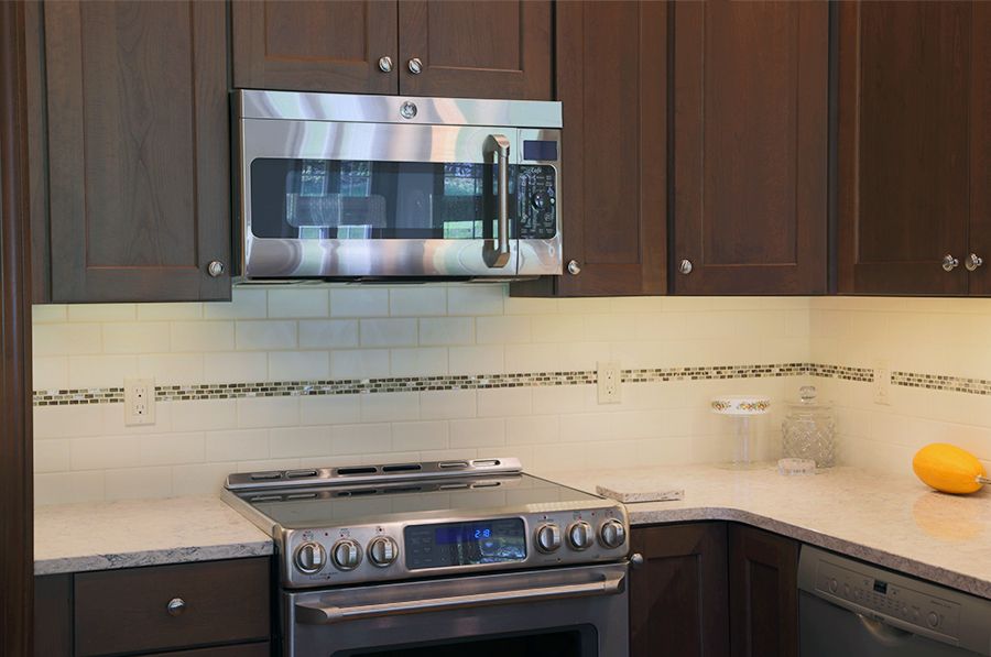 A modern kitchen setup featuring a stove and microwave with wooden cabinets and a sleek countertop.