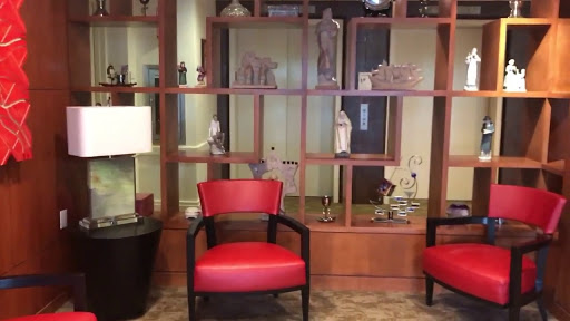 A stylish waiting area featuring red chairs and a decorative shelving unit.