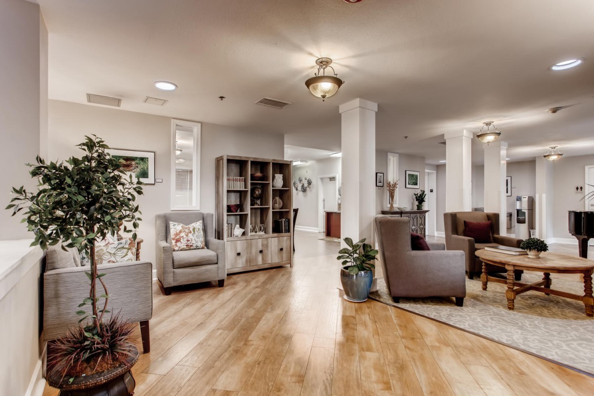 A cozy and well-decorated lobby area featuring comfortable seating, a bookshelf, and elegant lighting on hardwood floors.