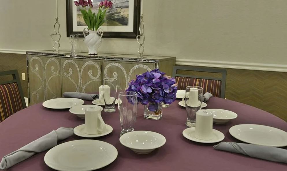 A elegantly set dining table with a floral centerpiece and candles.
