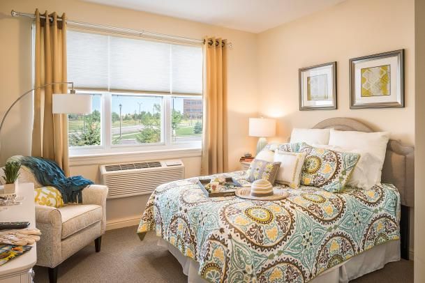 A cozy bedroom with patterned bedding and ample natural light streaming through the window.