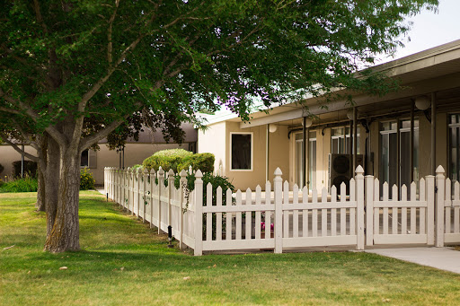 A cozy house with a white picket fence surrounded by lush greenery.