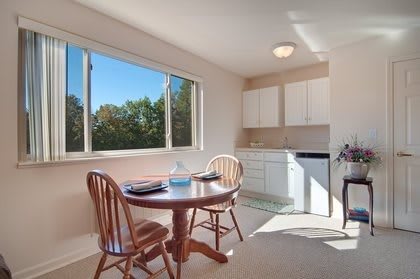 A cozy kitchen and dining area with a table set by the window, letting in ample sunlight.