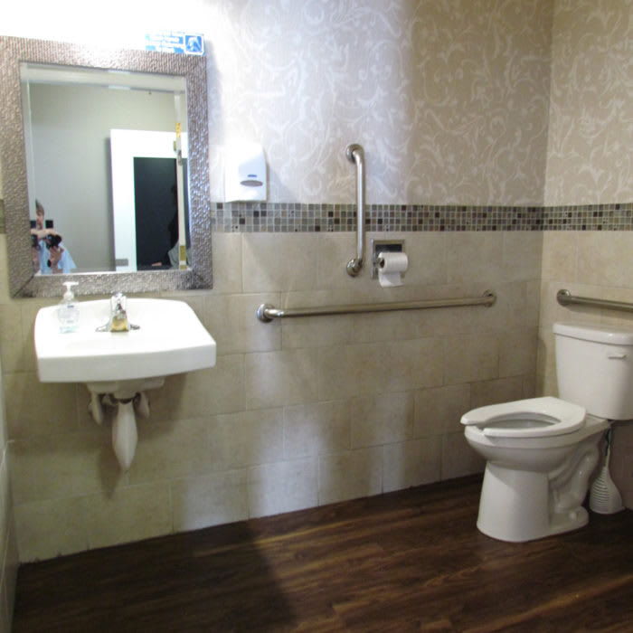 A modern accessible bathroom with a sink, toilet, and grab bars.