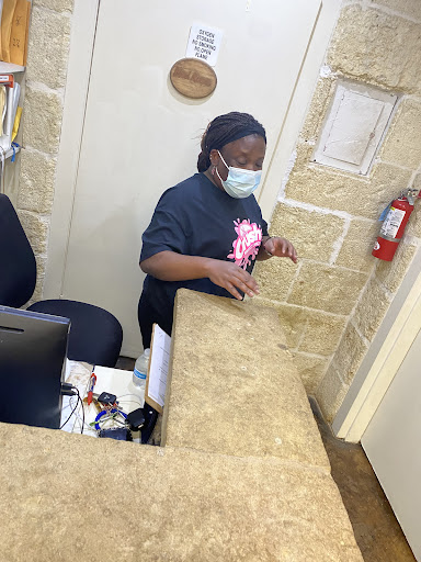 A receptionist assisting at the front desk while wearing a mask.