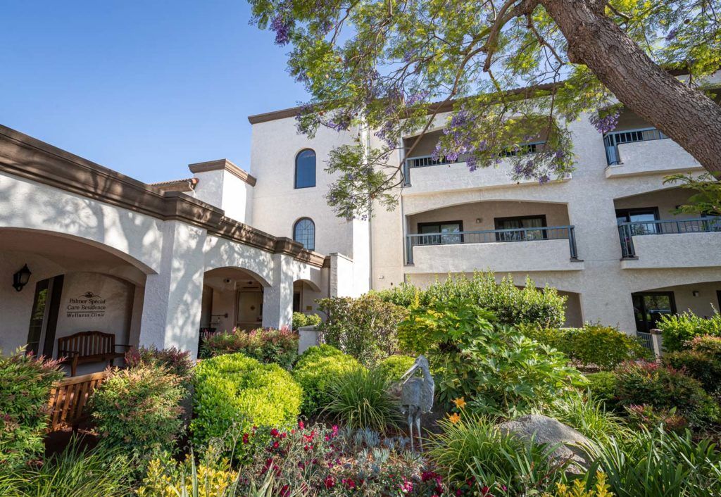 A sunny day view of a residential building with lush gardens and balconies.