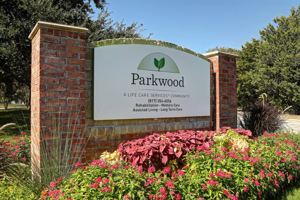 A brick sign for Parkwood surrounded by vibrant landscaping.