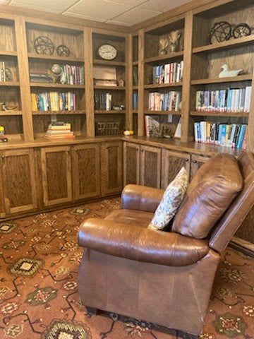 A cozy library with a leather chair and wooden bookshelves filled with books.