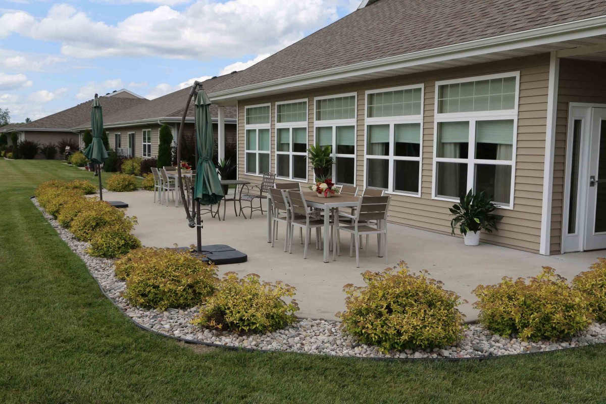 A spacious patio with outdoor furniture and landscaping in front of a house.