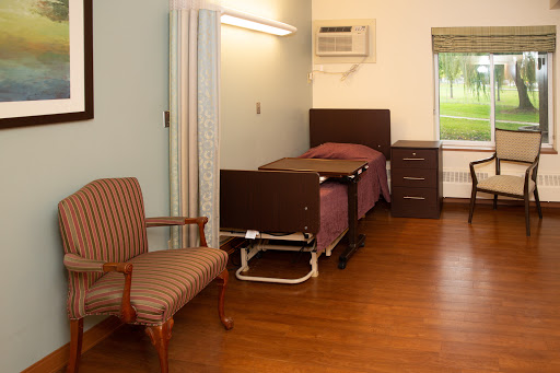 A simple hospital room featuring a bed, chair, and basic furnishings.
