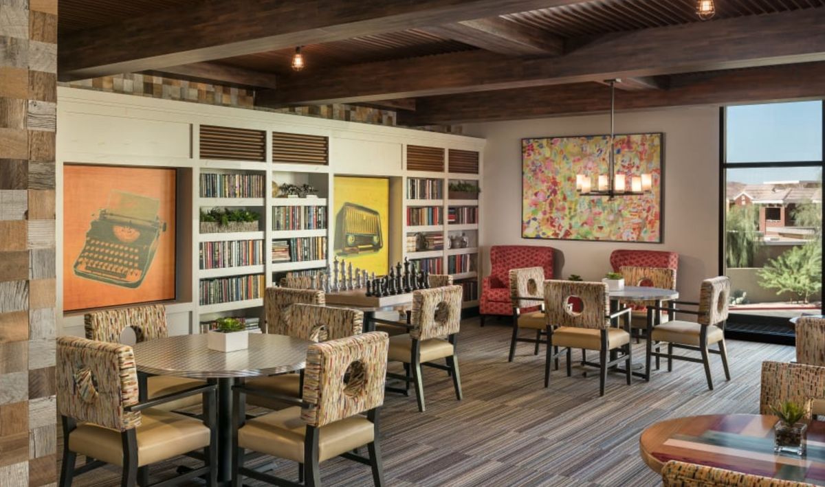 A cozy restaurant interior with bookshelves, casual seating, and decorative lighting.